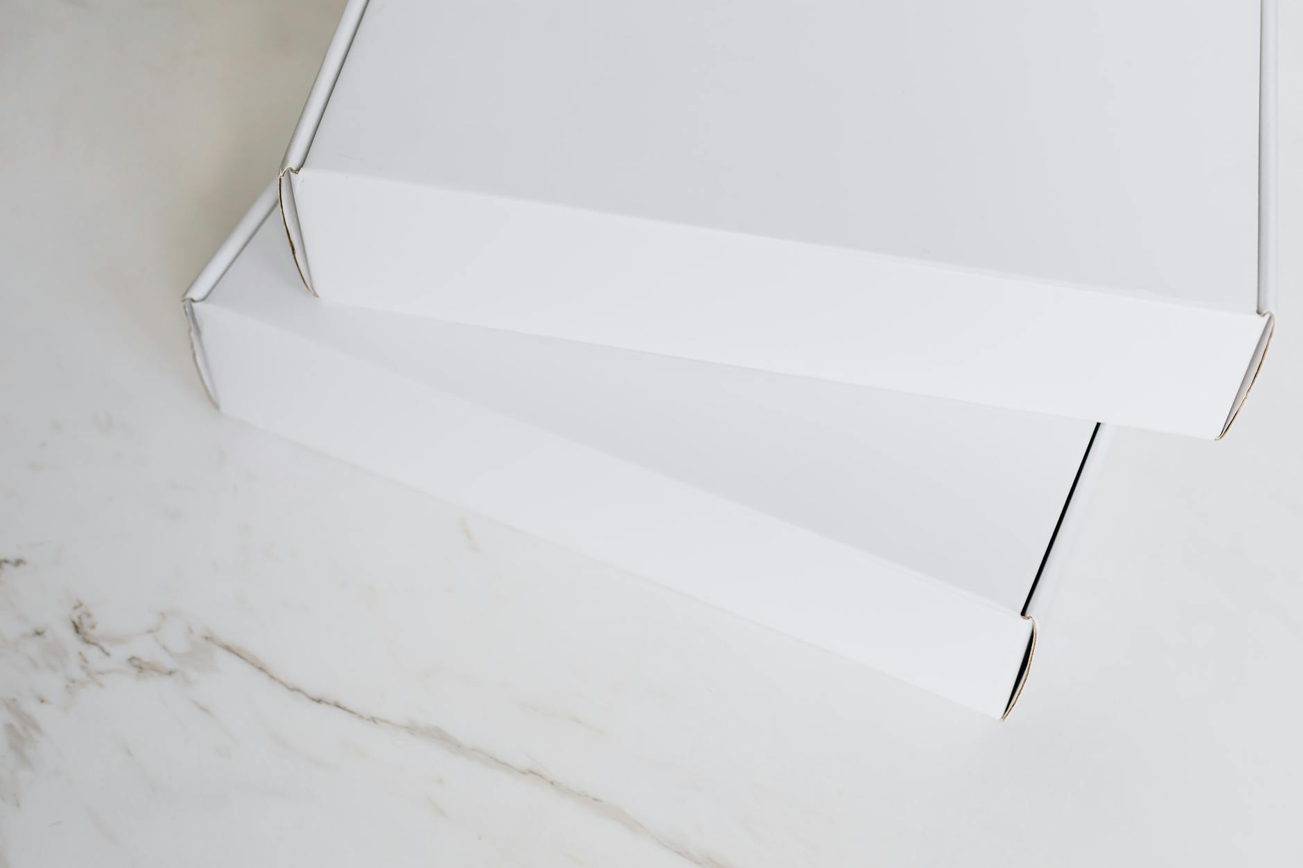 Two white cardboard boxes neatly stacked on a marble surface, ideal for online retail imagery.