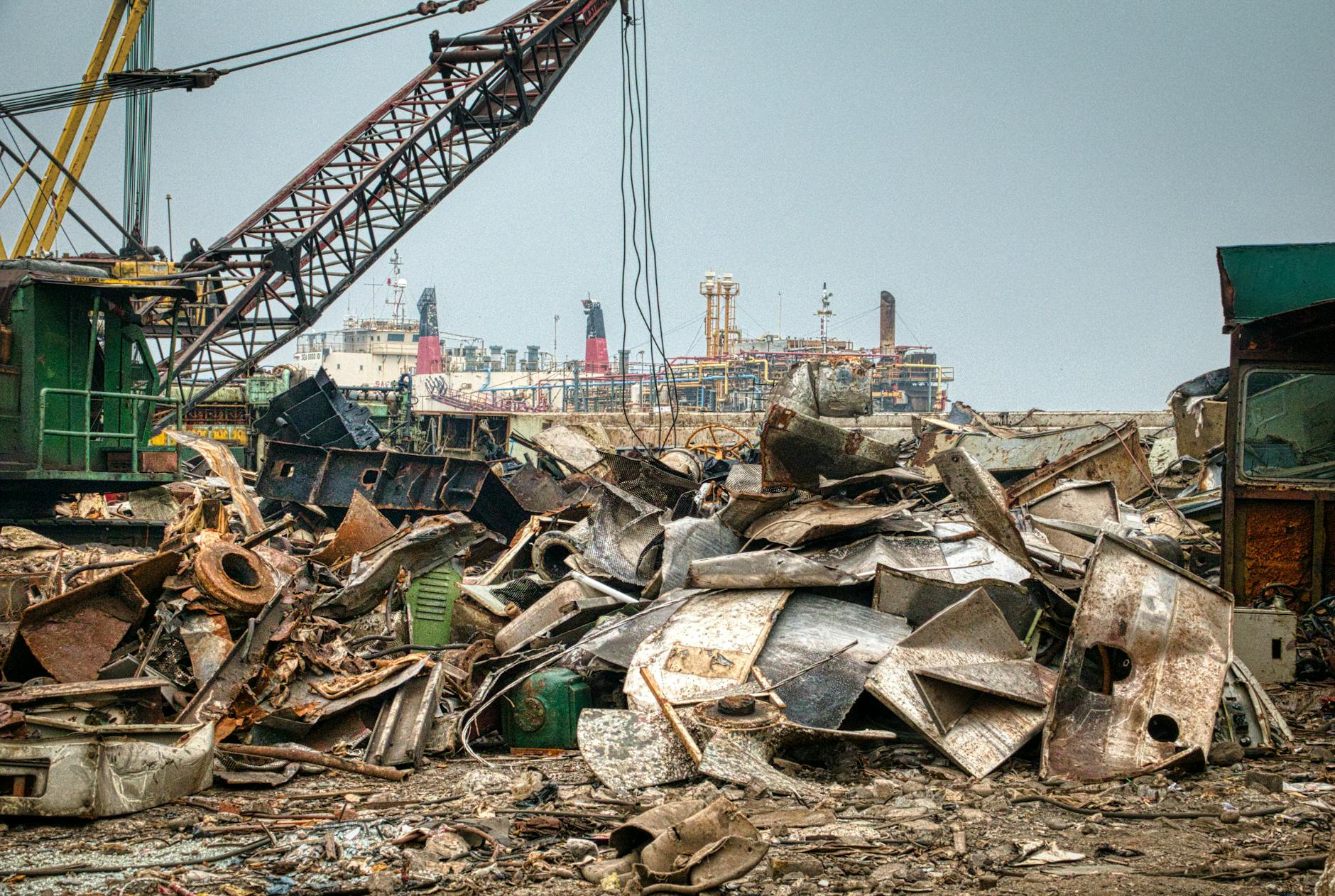 Rusty metal debris and cranes at a shipyard in Jakarta harbor, Indonesia.