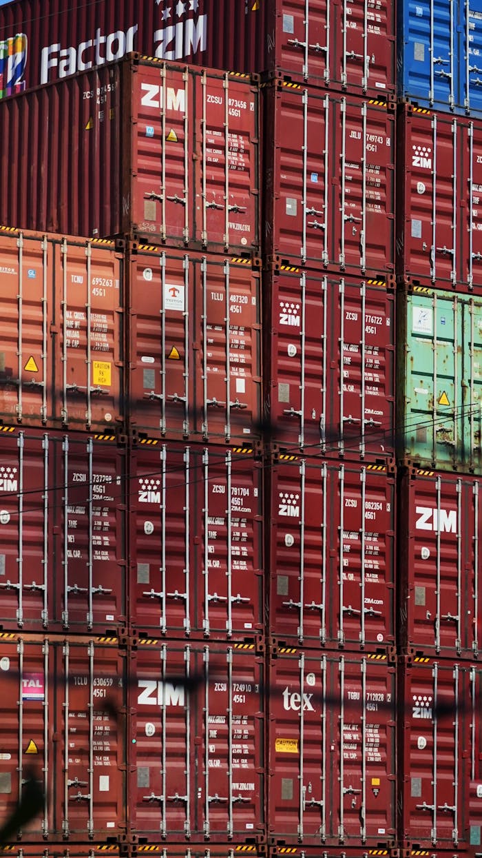 Vertical shot of colorful, stacked shipping containers at a bustling cargo port.