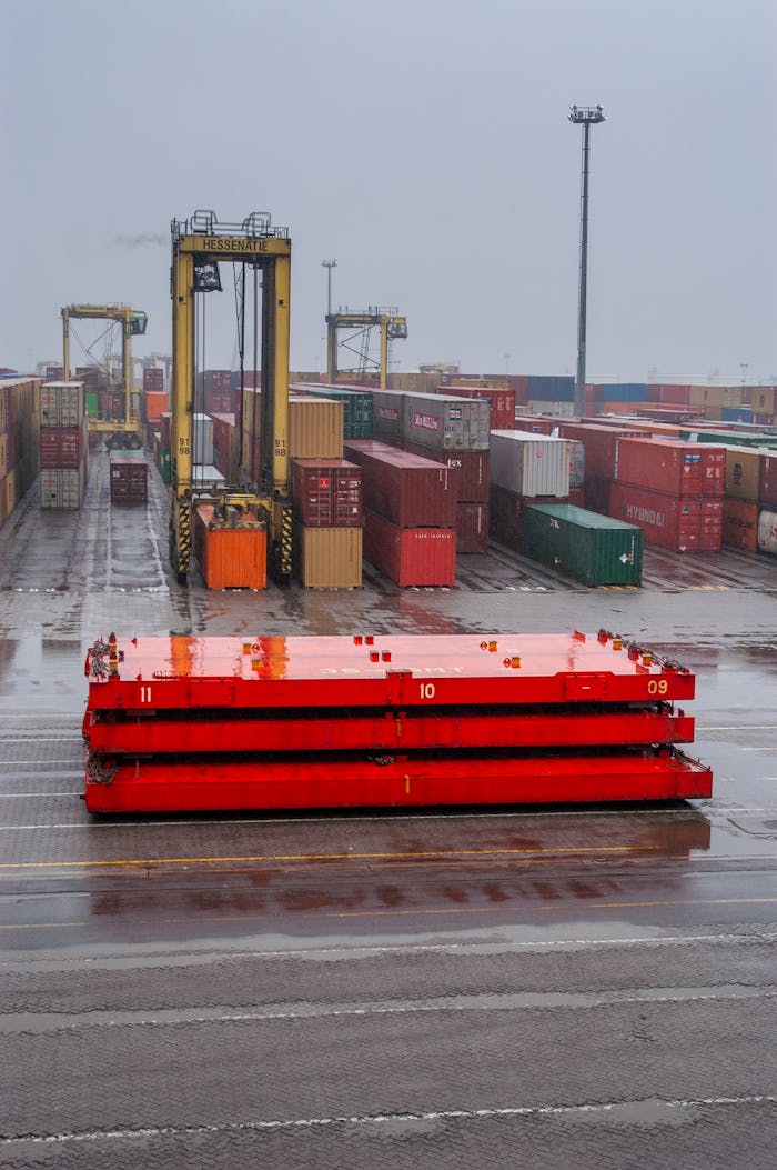 A port crane managing containers in a shipping yard during a rainy day.