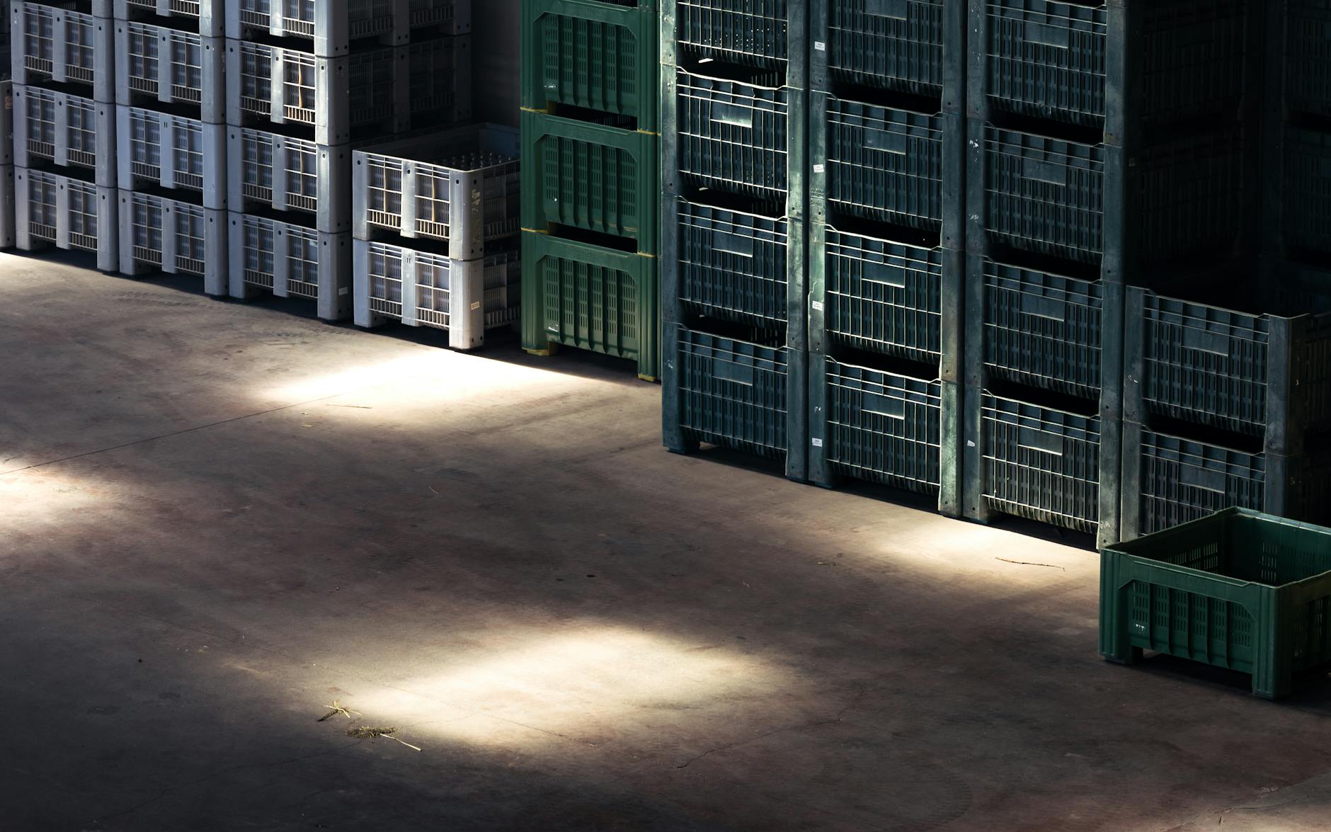 Sunlight streaming onto stacked crates in a warehouse, creating contrasting shadows and highlights.
