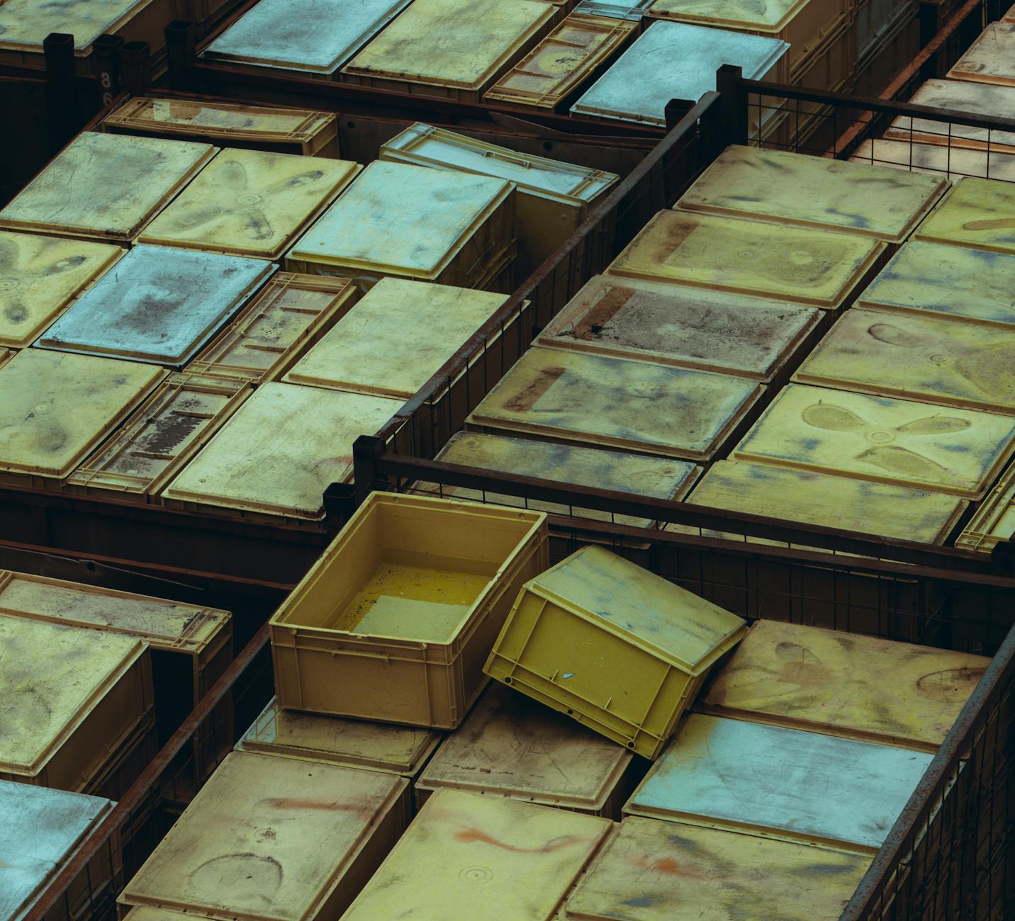 Overhead view of yellow and weathered plastic storage bins arranged neatly.